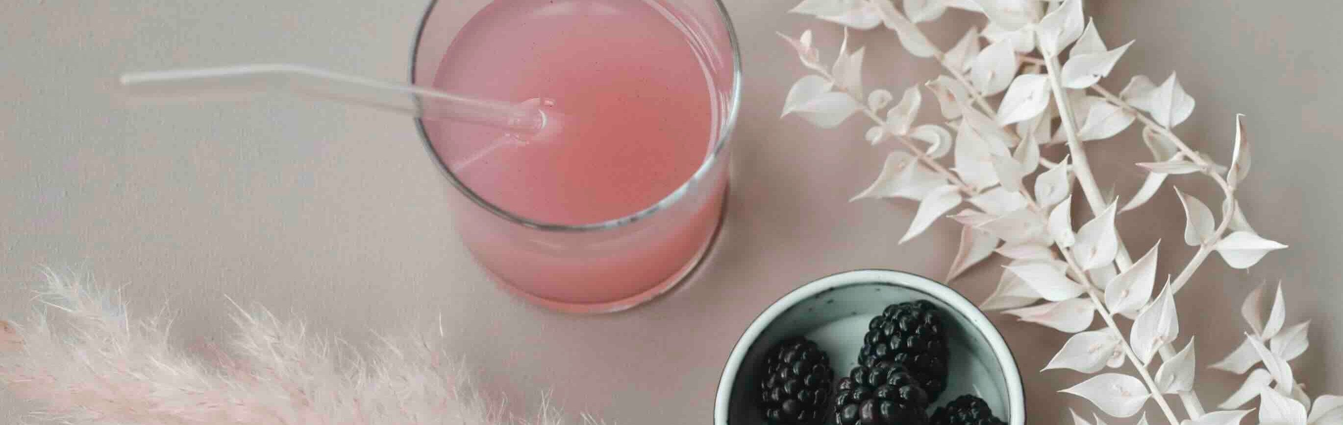 Ein Glas des erfrischenden Wildberry Collagen Drinks von Beautyhacker, begleitet von frischen Brombeeren. Der Drink sorgt für strahlende Haut, stärkt Haar und Nägel und passt perfekt in deine tägliche Beauty-Routine.